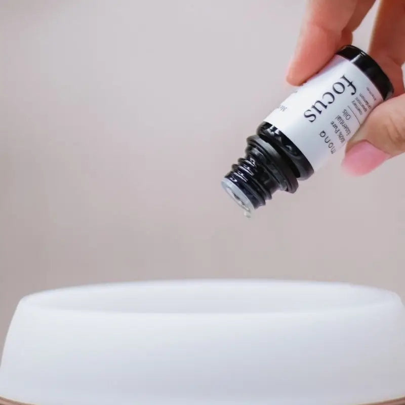 Lifestyle of hand holding Focus Essential Oil Blend 10ml MONQ over a diffuser