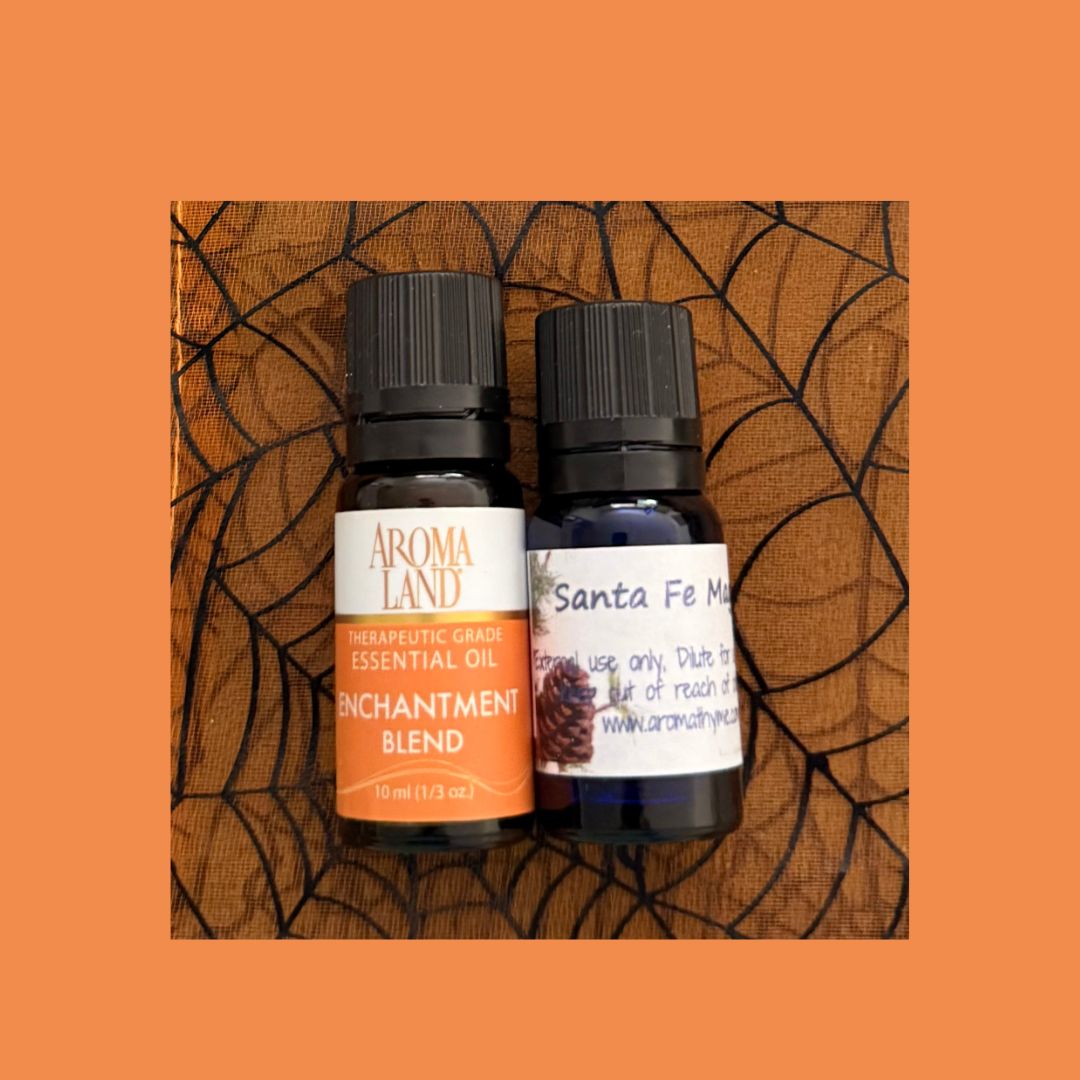 Two essential oil bottles labeled 'Aroma Land' and 'Santa Fe Magic' on a textured orange background.