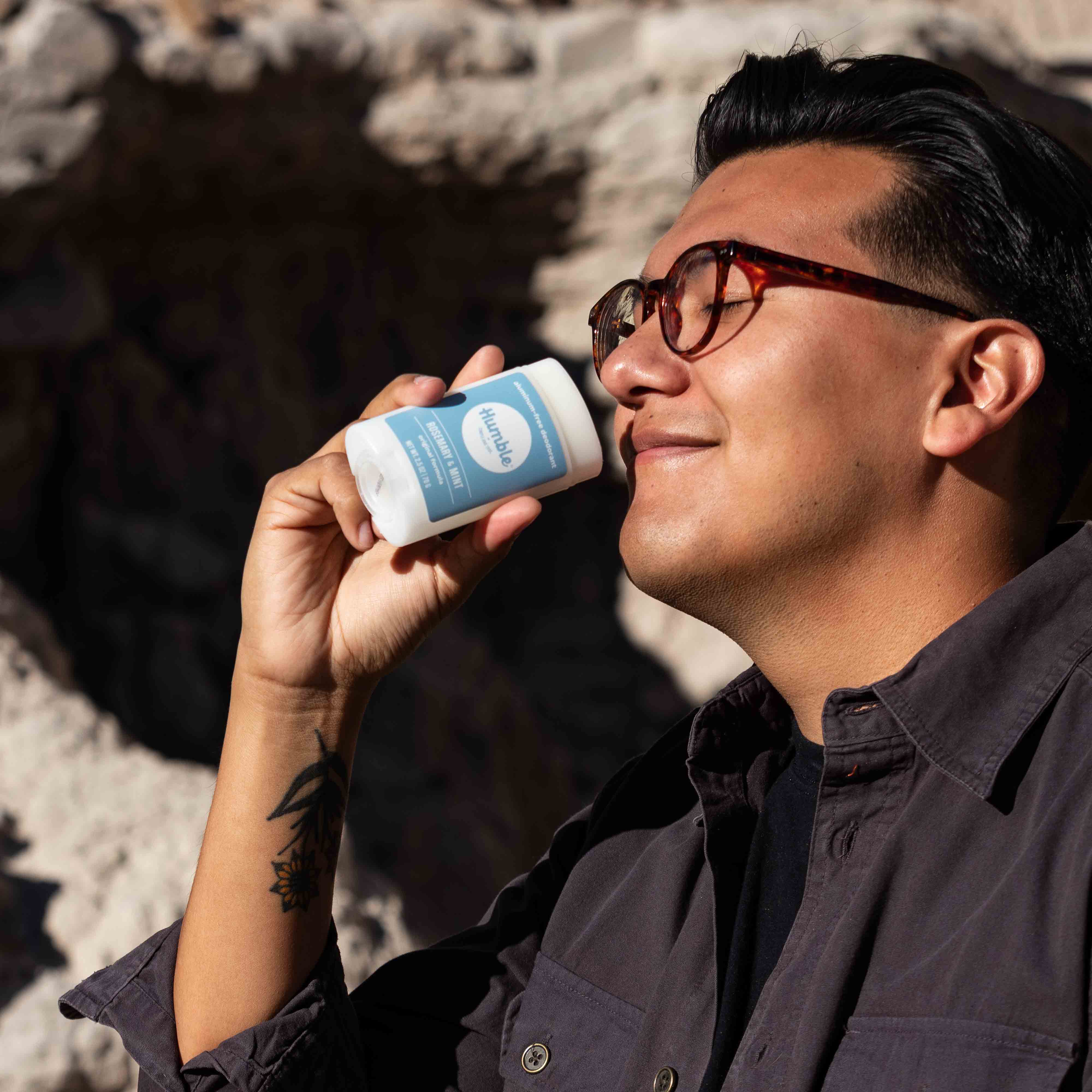 Man outdoors smelling and holding Humble original formula deodorant – Rosemary & Mint scent, aluminum free www.aromathyme.com