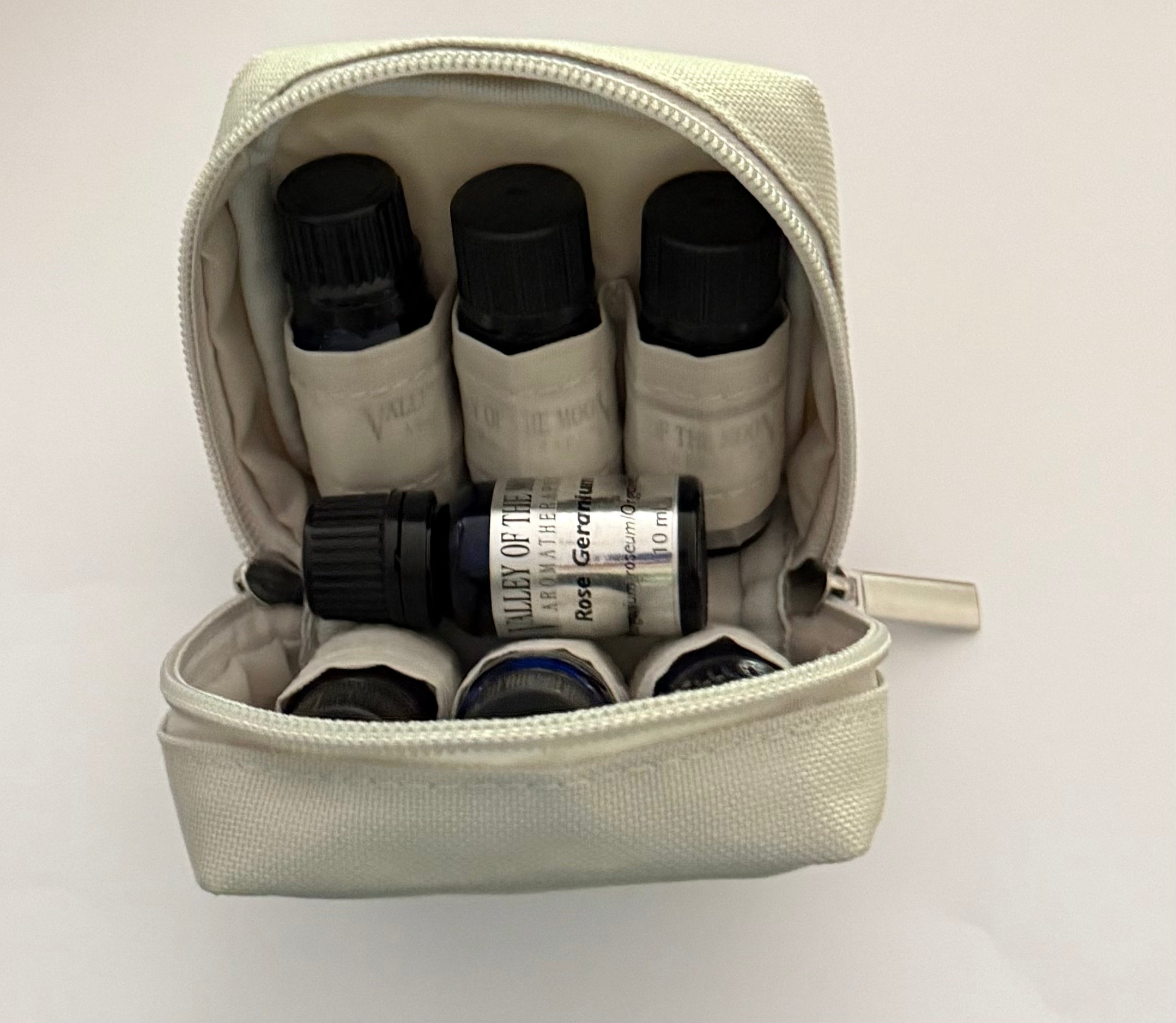 Small beige zipper pouch with essential oil bottles on a white background
